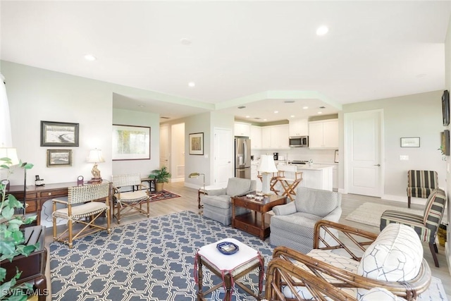 living room featuring recessed lighting, baseboards, and light wood finished floors