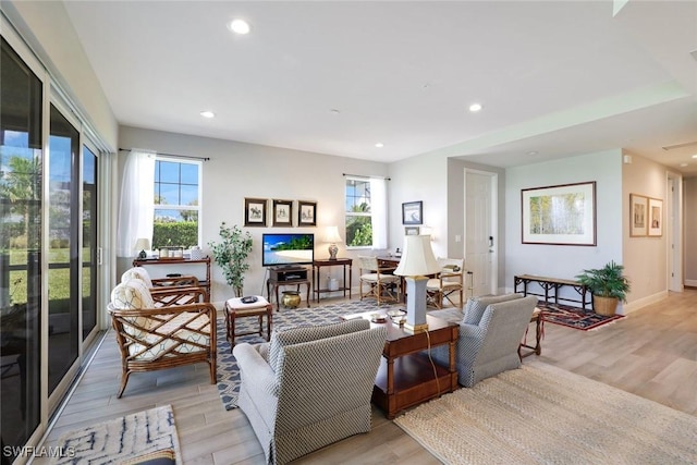 living area featuring a wealth of natural light, recessed lighting, and light wood finished floors