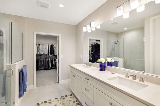 bathroom featuring a walk in closet, visible vents, a stall shower, and a sink