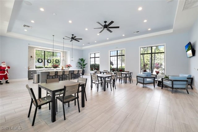 dining room featuring a raised ceiling, plenty of natural light, and visible vents