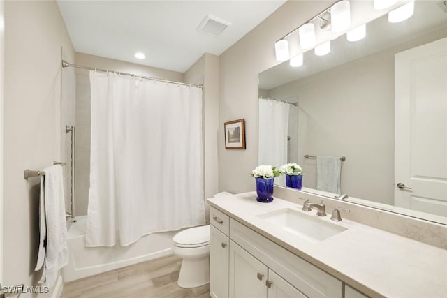 full bath with visible vents, toilet, shower / tub combo with curtain, wood finished floors, and vanity