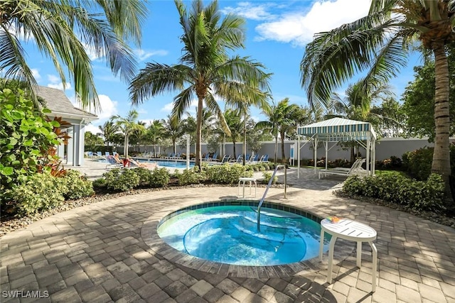 community pool with a gazebo, a hot tub, a patio, and fence