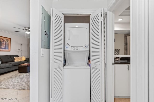 laundry area featuring a ceiling fan, a sink, tile patterned flooring, stacked washer / drying machine, and laundry area