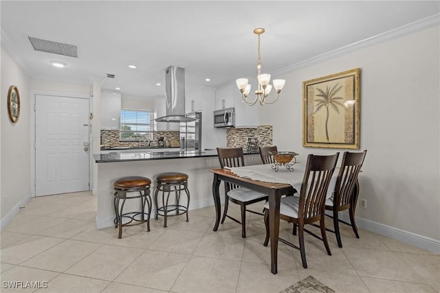 dining space featuring light tile patterned floors, visible vents, baseboards, and crown molding