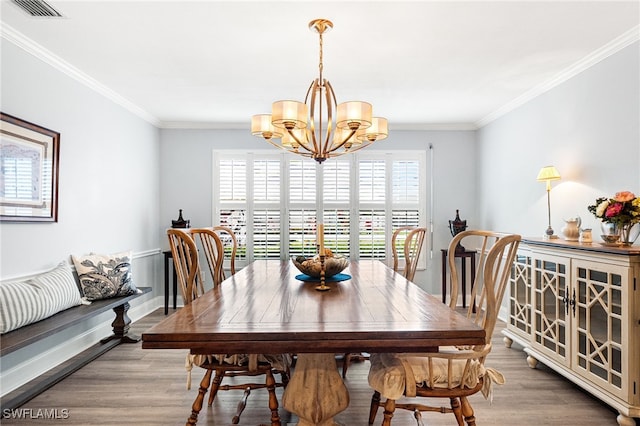 dining room featuring light wood-style flooring, a notable chandelier, visible vents, baseboards, and crown molding