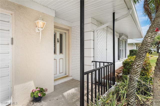 property entrance with brick siding and a porch