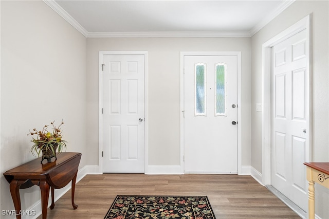 entryway with light wood-style floors, ornamental molding, and baseboards