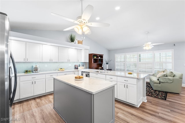 kitchen featuring stainless steel appliances, light wood-style flooring, white cabinetry, a sink, and a peninsula