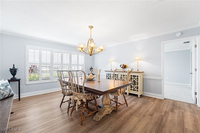 dining space featuring ornamental molding, a notable chandelier, and wood finished floors