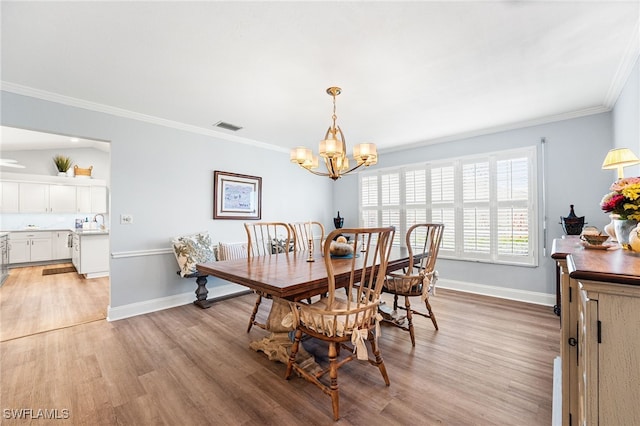 dining room featuring ornamental molding, light wood-type flooring, visible vents, and baseboards