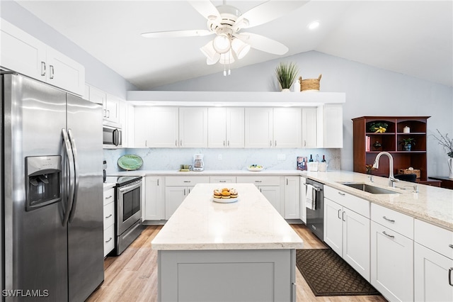 kitchen with lofted ceiling, a kitchen island, appliances with stainless steel finishes, and a sink