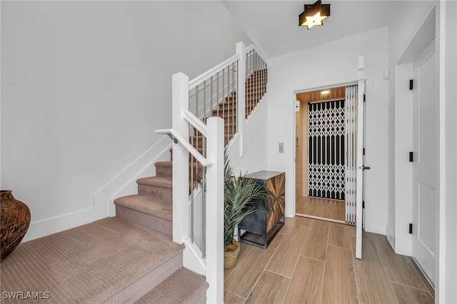 foyer entrance featuring stairs, baseboards, and wood finished floors