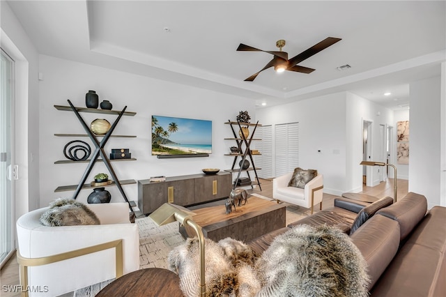 living area featuring a tray ceiling, recessed lighting, visible vents, a ceiling fan, and wood finished floors