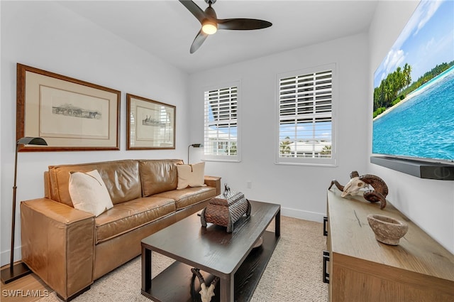 living area featuring a ceiling fan and baseboards