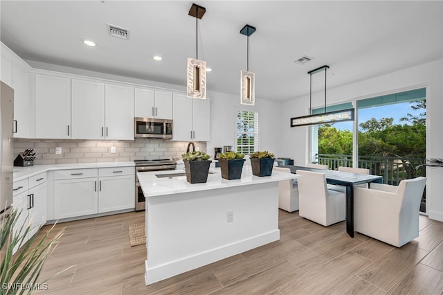 kitchen with stainless steel appliances, tasteful backsplash, light countertops, visible vents, and white cabinetry