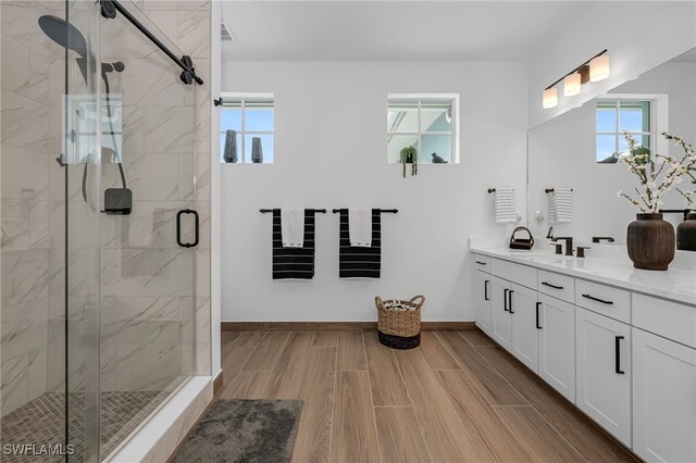 full bath featuring plenty of natural light, a shower stall, baseboards, and vanity