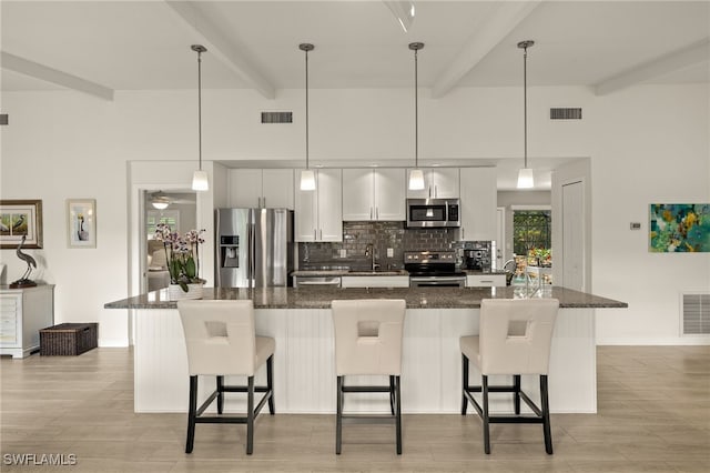 kitchen featuring visible vents, backsplash, appliances with stainless steel finishes, and a breakfast bar