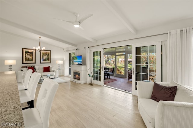 living room with a glass covered fireplace, lofted ceiling with beams, ceiling fan with notable chandelier, and light wood-type flooring