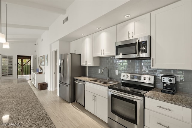 kitchen featuring a sink, stainless steel appliances, beam ceiling, and dark stone countertops