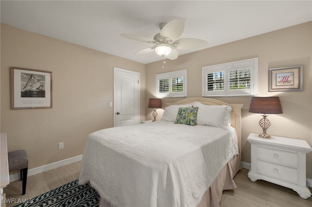 bedroom with a ceiling fan, light wood-type flooring, and baseboards