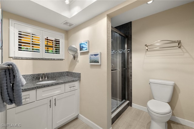 full bath featuring vanity, visible vents, baseboards, a shower stall, and toilet