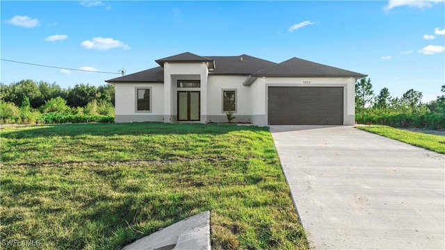 prairie-style house with a garage, concrete driveway, a front yard, and stucco siding