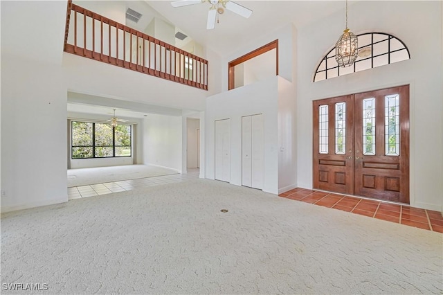 tiled foyer with carpet floors, visible vents, a high ceiling, and ceiling fan with notable chandelier