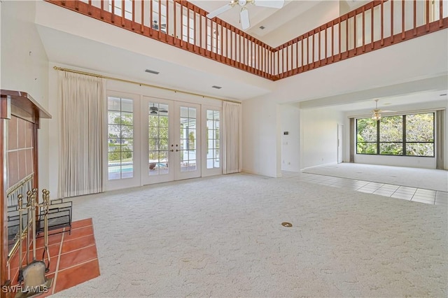 unfurnished living room featuring french doors, a high ceiling, carpet flooring, and a ceiling fan