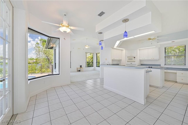 kitchen featuring light tile patterned floors, white microwave, a ceiling fan, visible vents, and white cabinets