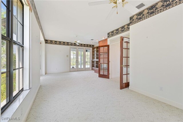 empty room with french doors, carpet flooring, visible vents, and a ceiling fan