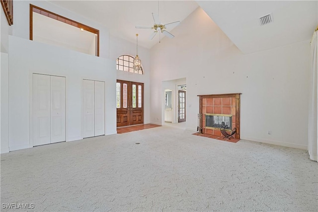 entrance foyer with ceiling fan, high vaulted ceiling, a tile fireplace, visible vents, and carpet