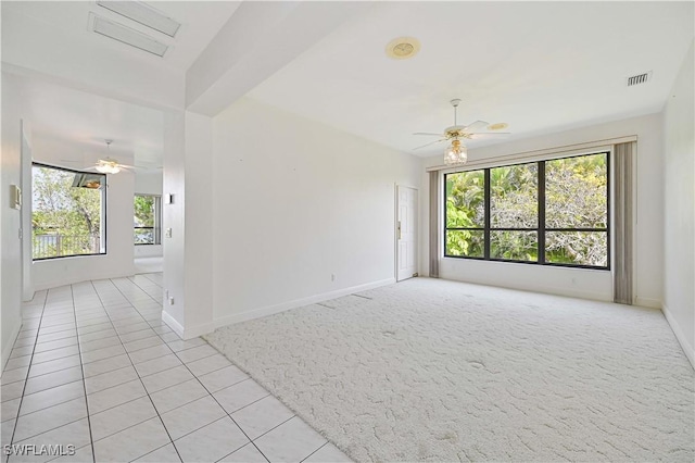 unfurnished room with ceiling fan, light tile patterned flooring, visible vents, and baseboards