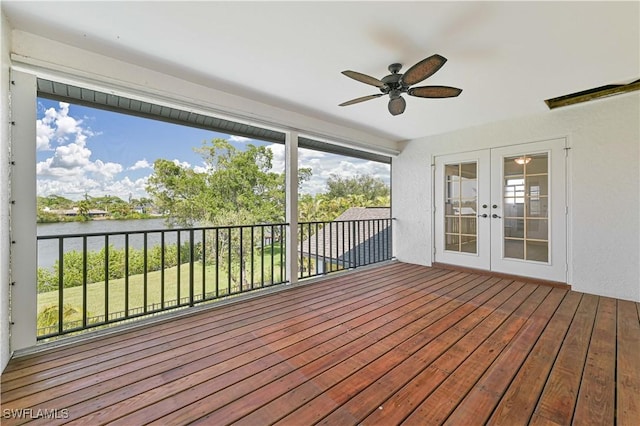 unfurnished sunroom featuring french doors, a water view, and a ceiling fan