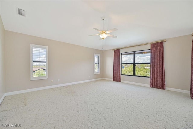 empty room with light carpet, a ceiling fan, visible vents, vaulted ceiling, and baseboards