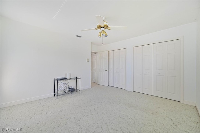 unfurnished bedroom featuring carpet, visible vents, baseboards, and two closets