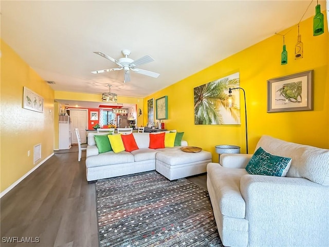 living area with a ceiling fan, dark wood-style flooring, visible vents, and baseboards