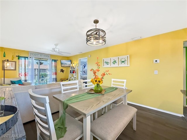 dining space featuring dark wood-style flooring, visible vents, baseboards, and ceiling fan with notable chandelier