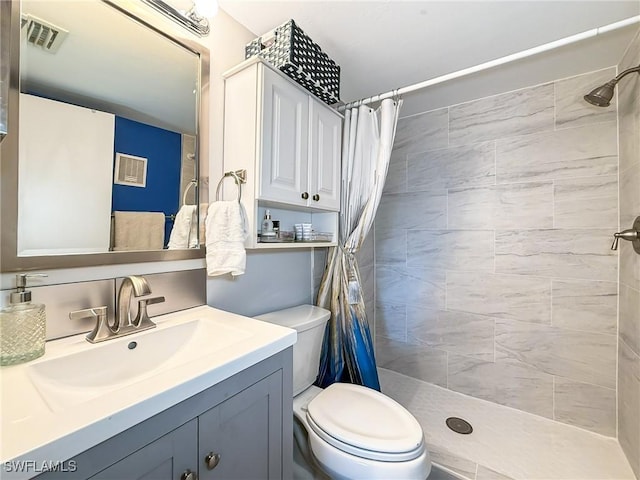 bathroom with toilet, visible vents, a tile shower, and vanity