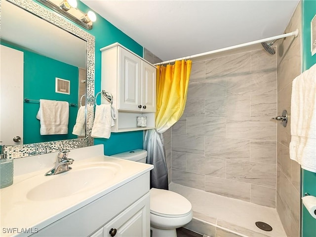 bathroom with visible vents, vanity, a tile shower, and toilet