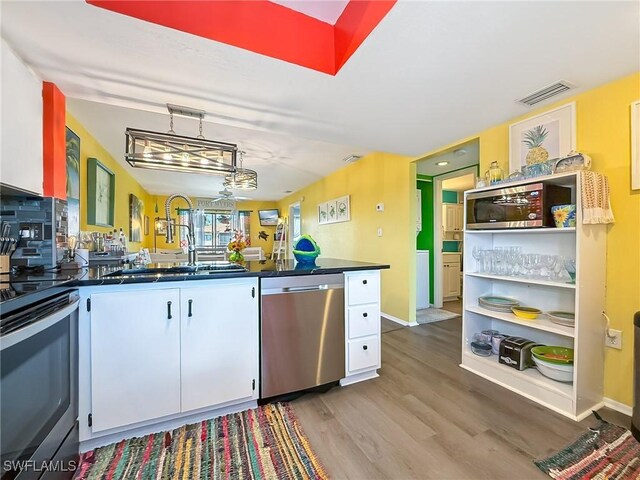 kitchen with a sink, visible vents, white cabinetry, appliances with stainless steel finishes, and dark countertops