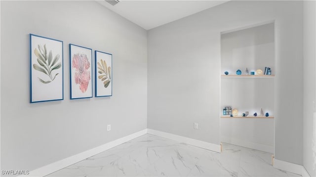 spare room featuring baseboards and marble finish floor