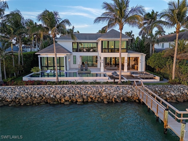 back of house with a water view, a swimming pool, an outdoor living space, and a patio