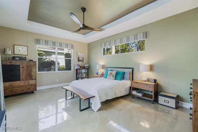 bedroom featuring multiple windows, baseboards, and a tray ceiling