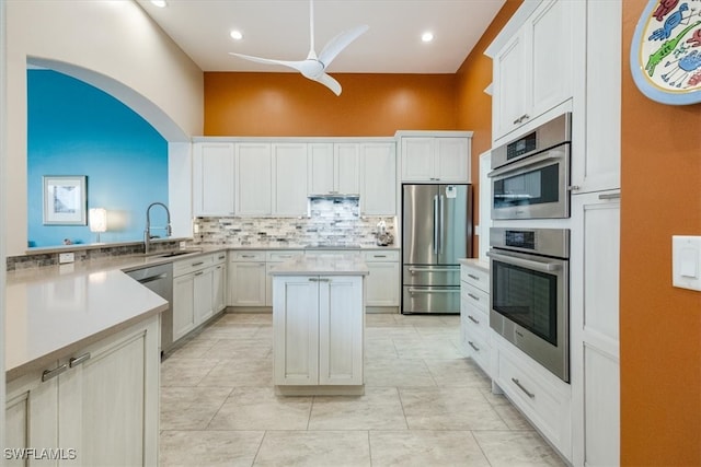 kitchen with a ceiling fan, a sink, tasteful backsplash, stainless steel appliances, and light countertops