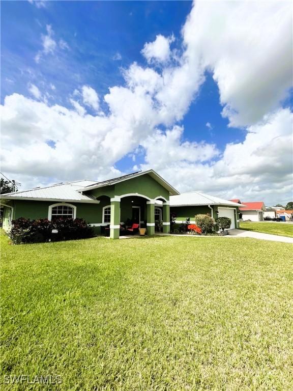 single story home featuring driveway, a front lawn, an attached garage, and stucco siding