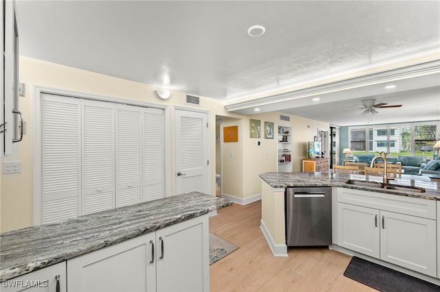 kitchen featuring visible vents, light wood-style flooring, white cabinets, a sink, and dishwasher