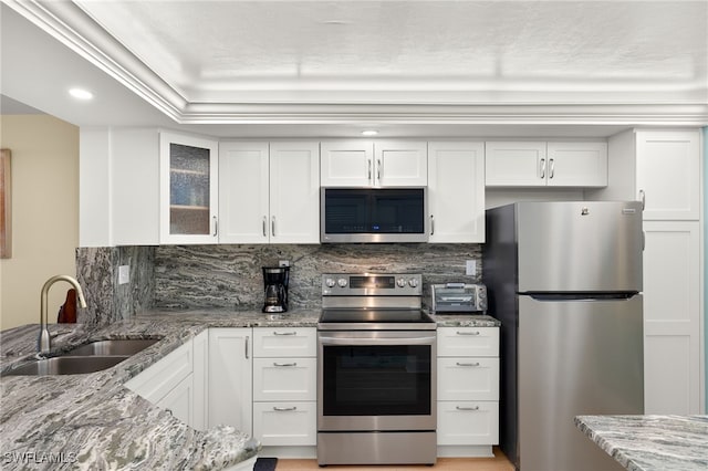 kitchen featuring appliances with stainless steel finishes, white cabinetry, a sink, and tasteful backsplash