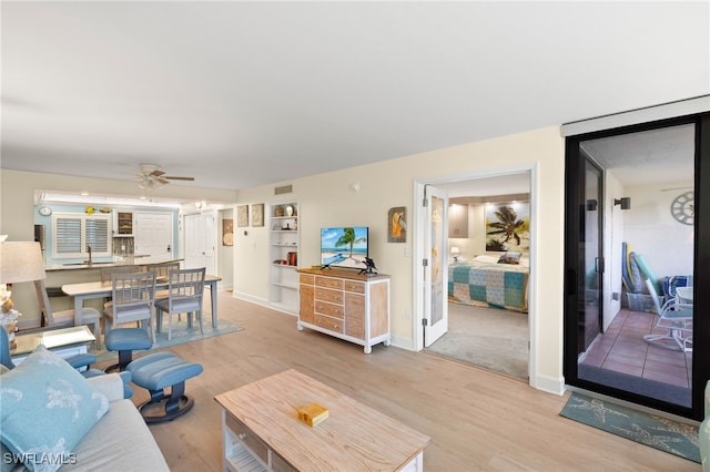 living room featuring baseboards, ceiling fan, visible vents, and light wood-style floors