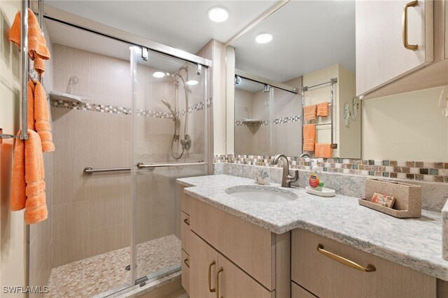 full bathroom with a stall shower, backsplash, and vanity