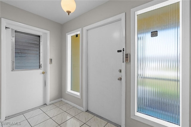 doorway to outside featuring baseboards and light tile patterned flooring